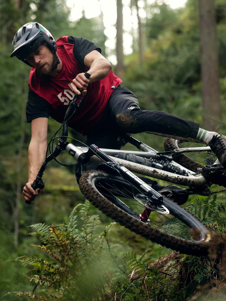 An Airdrop Edit being ridden on a steep, muddy trail in the woods